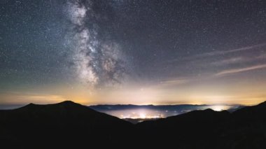 Samanyolu Galaksisi yıldızları ile dağlarda yıldızlı gece gökyüzü hızla hareket ediyor. Gece gündüz Astronomi Zamanı. Panoramik manzara, eğik, yüksek kalite 4k