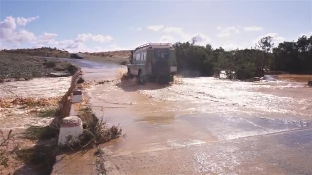 アフリカの豪雨の嵐の後に橋の上に氾濫した泥だらけの川を横断するすべての地形オフロード車モロッコ国 旅行冒険の背景 — ストック動画