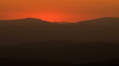 Renkli bir sabah, yaz doğasında dağların üzerinden portakal renkli bir gün doğumu. Zaman aşımı, kapanış, arkaplan. 
