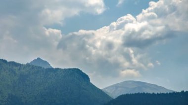 Baharda yeşil orman dağları üzerinde hareket eden dramatik fırtına bulutları. Zaman aşımı, yakınlaş, yukarı eğ. 