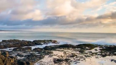 Günbatımı gökyüzünün renkleri ve okyanus kıyısındaki kumsallarda dalgalar Yeni Zelanda 'nın kuzey adasının vahşi doğasında. Zaman aşımı, Pan, Eğil. 