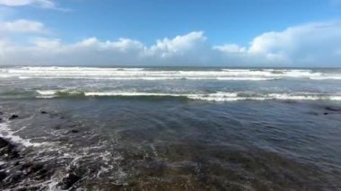 Boş Fas sahillerindeki güneşli yaz sahillerinde okyanus dalgaları hareket ediyor. Yavaş çekim 60 fps, yakınlaştır. 