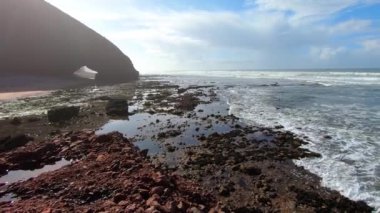 Fas kayalık okyanus kıyılarındaki boş Legzira sahilinde güneşli bir yaz günü. Yavaş çekim, soldan sağa çevir.. 