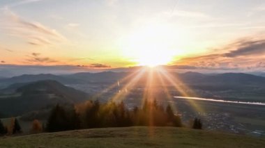 Avrupa 'da sonbahar sabahı, Alp Dağları' ndaki küçük bir şehrin üzerinde güneş ve güneş ışığıyla gün doğumunun güzel renkleri. Zaman Lastiği, Eğil. 
