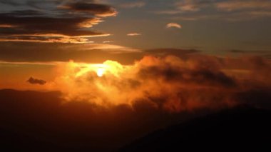 Altın gün doğumu, bulutlar gökyüzü, güneş doğmadan önce, dağların siluetinde.