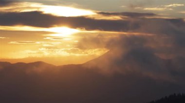 Sihirli sabah doğasında, gizemli dağlarda altın gökyüzü. Huzurlu gündoğumunda hızlı hareket eden bulutlar. Seyahat macerası arka plan