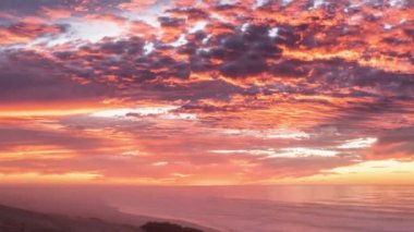 Kanlı kızıl gökyüzü bulutları Yeni Zelanda 'da okyanus kıyısında güzel bir gün doğumunda. Zaman aşımı 