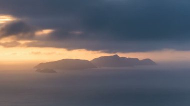 Mavi okyanus sularındaki küçük adalar üzerinde hızla hareket eden dramatik bulutlar Yeni Zelanda kıyılarında güneşli bir sabah gündoğumunda. Zaman aşımı, yakınlaştır. 