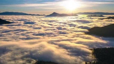 Güneşin doğuşunun güzel renkleri güneş ve bulutlar ile vahşi orman dağları üzerinde gizlenmiş sis ve güneşli sabah manzarası. Zaman aşımı, yukarı eğilme, hava görüşü aşırı hızlanma. 