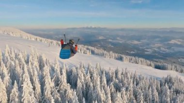 Alp sisli dağlarda donmuş kış ormanlarının üzerinde uçan yamaç paraşütlerinin güzelliği. Adrenalin açık hava macerası ekstrem spor, serbest uçuş özgürlüğü, kamerayı takip et.