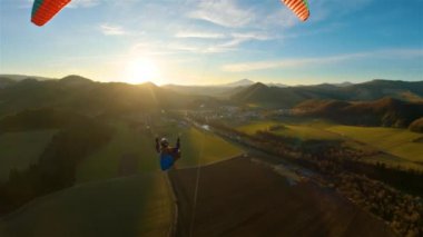 Baharın doğasında, yeşil kırsal kesimde, altın günbatımında destansı Paragliding uçuşu. Paraglider uçuşu, aksiyon kamerası, özgürlük adrenalin macerası