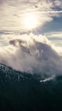 Pofuduk bulutların bahar dağları üzerinde hızlı hareket ettiği dikey video huzurlu doğanın güneşli manzarası. Açık alanda zaman aşımı arkaplanı