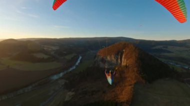 Bahar doğasında altın gün batımında huzurlu bir yamaç paraşütü. Serbest uçuş adrenalin sporunun özgürlük macerası.
