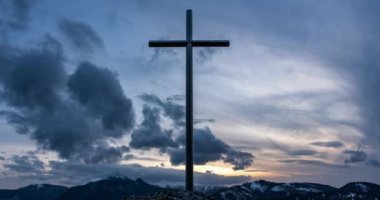 Akşam dağlarında Hristiyan çelik haçı üzerinde hızla hareket eden dramatik gri bulutlar. Doğa, dinin ve inancın sembolü. Zaman akıp gidiyor..