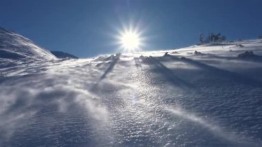 Rüzgar, kışın, rüzgarlı bir günde, donmuş dağlarda kar savurur. Panoramik düşük açı görünümü