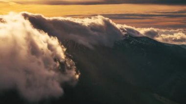 Alp dağlarının yamaçlarında ilerleyen gizemli tüylü bulutlar. Katabatik rüzgarda. Güzel altın günbatımı zaman atlamasında. 