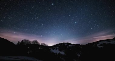 Mavi kış gecesi gökyüzünün büyüsü Samanyolu galaksisinin yıldızları doğada altın gündoğumundan önce hızla hareket ediyor. Zaman atlamalı astronomi, gece gündüz, 4k çözünürlüklü UHD