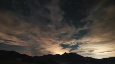 Samanyolu galaksisi yıldızları ve bulutlar yaz gecesi gökyüzünde Alp dağları üzerinde hızla hareket ediyor.