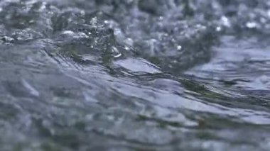 Nehir akıntısında kristal berrak su dalgalarının güzelliği, yavaş çekim doğa arka planı
