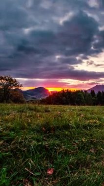 Güneşli bir yaz sabahı Avrupa 'da güneş ve bulutların hızlı bir şekilde orman dağları üzerinde hareket ettiği dikey bir günbatımı videosu. Zaman aşımı, yakınlaştır, sosyal ortam için ideal