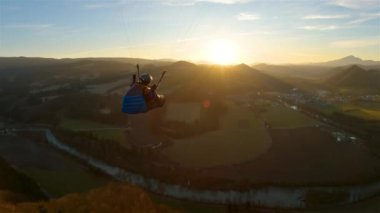 Sihirli altın günbatımında, bahar doğasının üzerinde Paragliding kanadında uçma özgürlüğü. Serbest uçuşun adrenalin macerası, aksiyon kamerasını takip et..