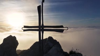 Hristiyan silueti, bulutların üstündeki altın gündoğumunda Alp Dağları 'nın tepesinden geçer. Huzurlu doğal din geçmişi.