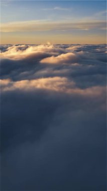 Altın gündoğumunda rüya gibi bulutların üzerinde uçmanın dikey hava görüntüsü. Sosyal medya için ideal bir açık hava macera seyahati hikayesi.