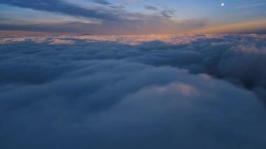 Güneşin doğuşundaki sisli manzaranın sihirli görüntüsü, mavi saatte rüya gibi bulutların üzerinde uçmak. Hava manzarası, özgürlük uçuşu arka plan.
