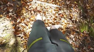 Sonbaharda bir orman yolunda yokuş aşağı giden bir insanın görüntüsü. Kuru yapraklar izleri ve doğal adımları örtüyor, sakin bir doğa yürüyüşü sahnesi yaratıyor altın mevsimlik tonlarda. 