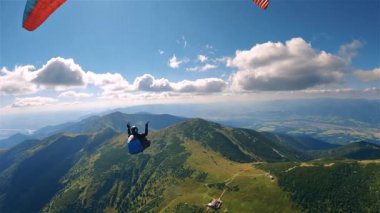 Yeşil Alpler dağ sırtlarının üzerinde uçan paraglider. Barışçıl bir hava yolculuğunda doğanın, özgürlüğün ve heyecanın mükemmel dengesi. Adrenalin dolu bedava yamaç paraşütü macerası