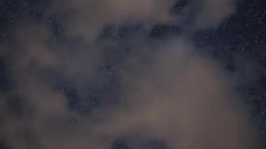 Yıldızlar, Samanyolu Galaksisi ve bulutlarla dolu gece gökyüzünün çarpıcı 4K zaman atlaması. Astronomi, belgeseller ya da meditasyon görselleri için mükemmel..