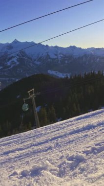 Zell am, Avusturya 'da güneşli bir kayak merkezinin dikey görüntüsü, teleferiği ve karlı bir dağ manzarası. Kayak ve dağ aktiviteleri için mükemmel bir kış mekanı. Yüksek kalite 4k