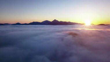 Puslu bulutların üzerindeki hızlı hareket doğanın güzel gündoğumunda yaz sabahı dağların silueti üzerinde. Hava görüntüsü, Hiper hata, yakınlaştır 