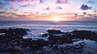 Doğanın gücü. Yeni Zelanda 'nın kayalık kıyılarında, okyanus kıyısında gün doğumunda güzel gökyüzü su dalgaları. Eğil. 