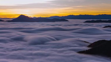 Destansı sabah doğası. Sis bulutları dalgaları Alp Dağları vadisinde hareket ediyor. Renkli gündoğumu gökyüzü ve sonbahar manzarasında güneş ışığı. Zaman aşımı, Pan görünümü 