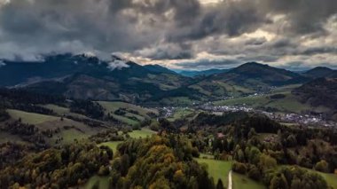 Huysuz gökyüzü ile sonbahar kırsalında zaman kaybı. Fırtına bulutları yukarıdan dağ manzarasına hücum ediyor. Mevsimsel değişim, hava durumu, seyahat görüntüleri ya da doğa geçmişi için mükemmel..