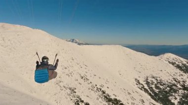 Paraglider, karlı alp sırtlarının üzerinde uçuyor. Göz kamaştırıcı hava manzarası. Özgürlüğe paraşütle atlamak. Takip kamerasıyla yakalanan bu klip ekstrem sporlar, kış seyahati, adrenalin macerası için ideal.