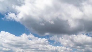 Beyaz ve karanlık bulutların zaman atlaması güneşli doğada mavi bir gökyüzünde sürükleniyor. Video projelerinde hava durumu, arkaplan ya da atmosferik geçiş için mükemmel. 