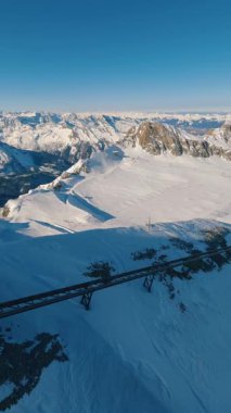 Kitzsteinhorn tepesinden kışın Kaprun Buzul kayak merkezinin dikey panoramik görüntüsü. Açık mavi gökyüzü, karlı yamaçlar, ve manzaralı güneşli alp manzaralı teleferik yapısı, ideal