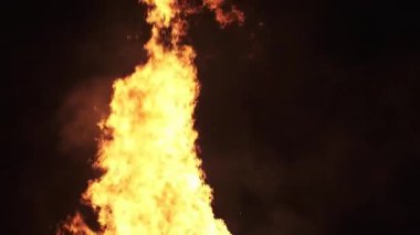 Büyük alevlerin yavaş çekimde siyah arka planda dans etmesi. Şenlik ateşinin parlak turuncu ve sarı tonları ısı, enerji, tutku ya da dramatik sinema için mükemmel sıcak ve ateşli bir etki yaratır.