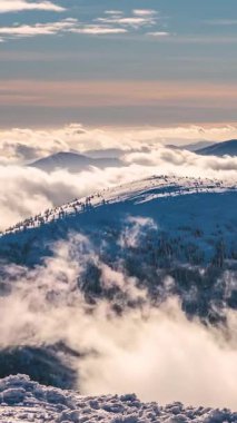 Kar kaplı dağ yamaçlarında ve donmuş ormanlarda alçak bulutların dikey zaman kayması. Sakin ve esrarengiz kış manzarası açık hava macerası, dağcılık, doğa veya