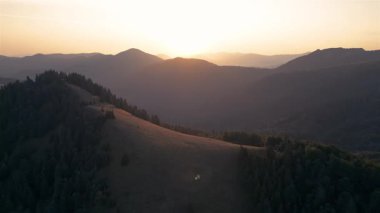Altın gündoğumu sırasında Karpat Dağları 'nın çarpıcı hava manzarası. Sıcak ışık, bu huzurlu sonbahar doğa manzarasındaki ormanlık tepelere ve vadilere dokunur. Sinematik kullanım için ideal.