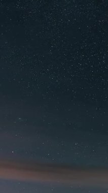 Hızla hareket eden bulutları olan karanlık yıldızlı bir gökyüzünün dikey zaman atlaması. Kozmik hareketi gösteren güzel astronomi sahnesi, bilim için ideal, uzay temaları veya sosyal medya için arka plan görüntüleri.