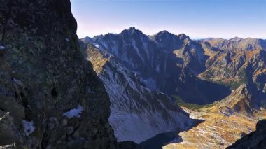 Sonbaharın sonlarında engebeli kayalık dağ zirvelerinin geniş panoramik manzarası. Altın yamaçlar, dik kayalıklar, ve dağlık vadiler çarpıcı bir açık hava macerası ortamı yaratır..