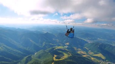 Yemyeşil dağ manzarası üzerinde paraşütle atlamak. Vadi ve orman manzaralı huzurlu bir termal uçuş. Açık hava, adrenalin macera, özgürlük, seyahat ya da ekstrem spor için mükemmel.