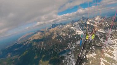Karlı Alpler 'in yukarısında paraşütle atlayan, nefes kesen dağ manzaralarını yakalayan ve termal hava akımlarında daireler çizen POV görüntüleri. Nihai özgürlük ve macera