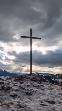 Karlı dağlardaki çelik bir zirvede hafif bir itme ile dikey zaman atlaması. Güneş ışığı, inancı ve engebeli dağları harmanlarken hızlı bulutlar dramatik bir kış gökyüzünü süpürüyor. Harika.