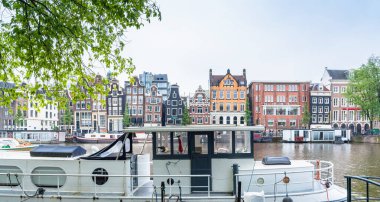 Amsterdam, Hollanda - 12 Haziran 2019: Amstel, Amsterdam, Hollanda 'da tipik Hollanda evleri, kanalları ve dükkanlarıyla gündüz manzarası.