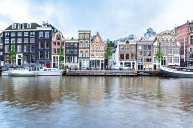 Amsterdam, Hollanda - 12 Haziran 2019: Amstel, Amsterdam, Hollanda 'da tipik Hollandalı evleri, kanalları ve dükkanları ile uzun süreli görünüm.