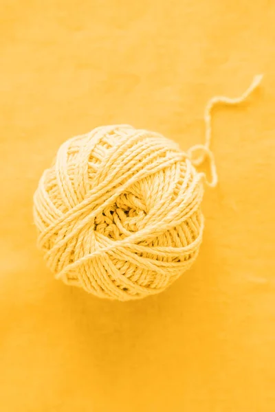 Ball of yellow woolen threads, close-up, top view. Sewing and needlework concept. Selective focus.